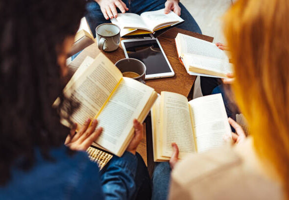 Diverse group of friends discussing a book in library.